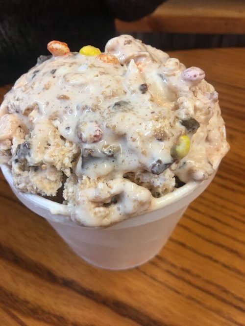 A cup filled with a creamy, chunky ice cream mixture topped with colorful candy pieces.