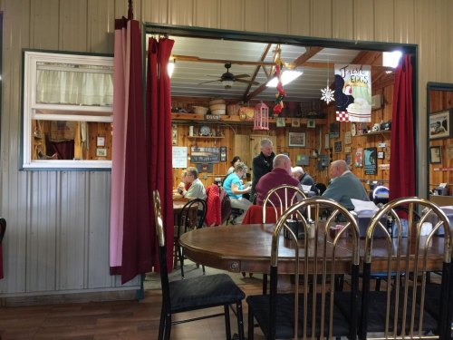 A cozy diner scene with patrons seated at tables, chatting and enjoying meals, framed by a doorway with red curtains.