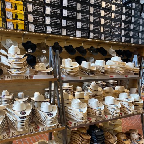 A display of various styles and colors of cowboy hats on shelves in a store.