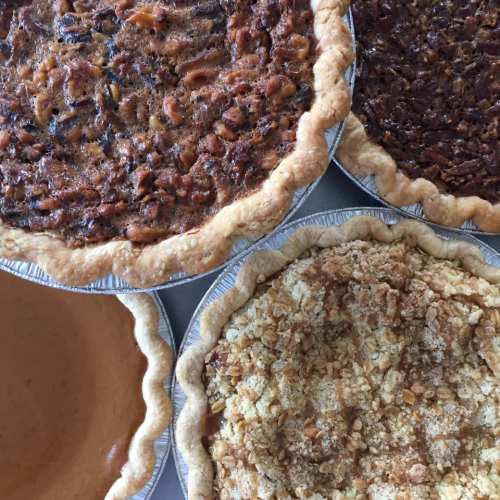 A variety of pies including pecan, pumpkin, and crumb-topped, arranged on a table.