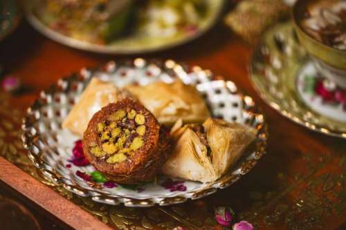 A decorative plate with assorted Middle Eastern sweets, including baklava and a round pastry filled with nuts.