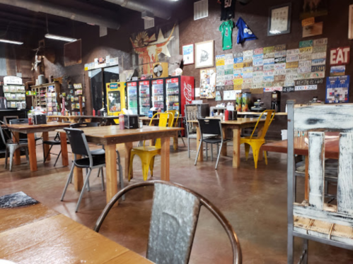 A rustic restaurant interior with wooden tables, metal chairs, and walls decorated with memorabilia and license plates.