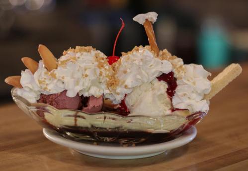 A delicious banana split topped with whipped cream, cherries, and crushed nuts in a glass dish.