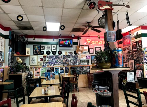 Cozy diner interior with colorful decor, vinyl records, and a TV, featuring wooden tables and a lively atmosphere.