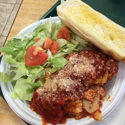 A plate of pasta with marinara sauce and cheese, served with a side salad and a piece of garlic bread.