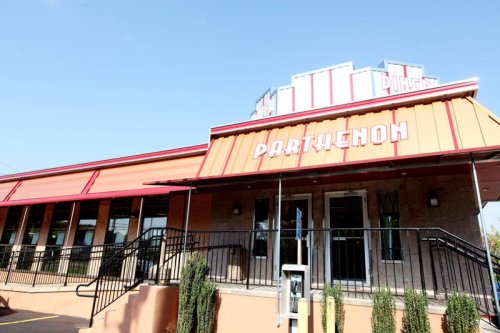 Exterior of a restaurant named "Parthenon," featuring a colorful awning and a clear blue sky.