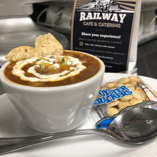 A bowl of chili topped with sour cream and green onions, served with a side of oyster crackers.