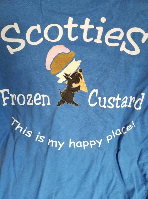 Blue t-shirt featuring "Scotties Frozen Custard" with a cartoon dog and ice cream cone, stating "This is my happy place!"