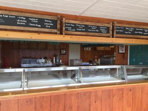 Ice cream shop interior with a wooden counter, glass display freezers, and a chalkboard menu of flavors above.