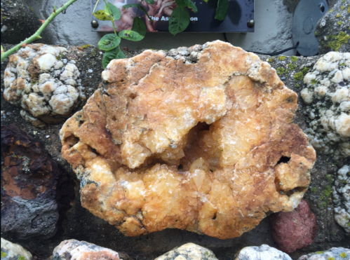 A large, textured rock with a golden-brown hue, embedded in a stone wall with various other rocks.