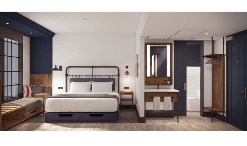 Modern hotel room featuring a bed, seating area, and stylish bathroom with wooden accents and contemporary decor.