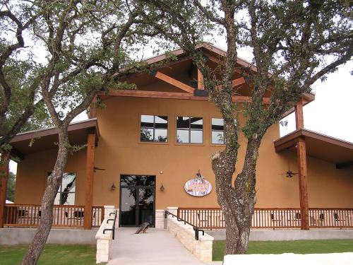 A modern building with a brown exterior, large windows, and wooden accents, surrounded by trees.