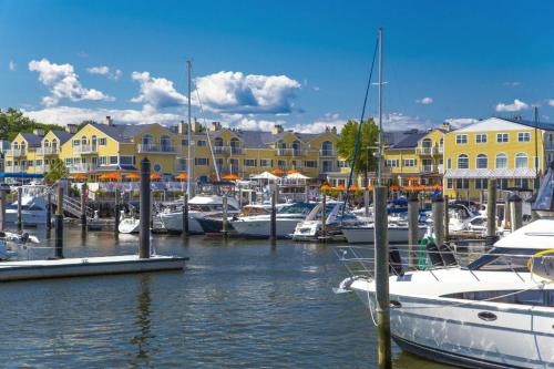 A marina with boats docked, surrounded by yellow buildings and blue skies with fluffy clouds.