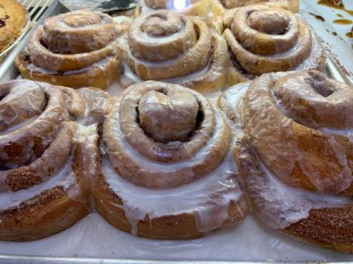 Freshly baked cinnamon rolls drizzled with creamy icing, arranged in a tray.
