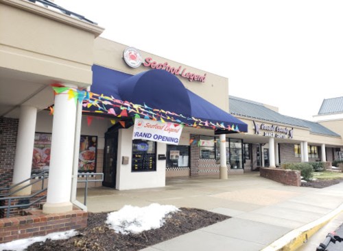 Exterior of Seafood Legend restaurant with a grand opening sign and colorful decorations. Snow on the ground.