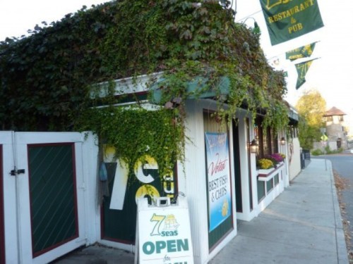 A charming restaurant and pub covered in greenery, with a sign indicating it's open for business.