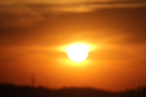 A blurred sunset with vibrant orange and yellow hues, casting a warm glow across the sky.