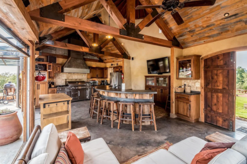 Spacious rustic kitchen with wooden beams, a large island, and modern appliances, featuring a cozy seating area.