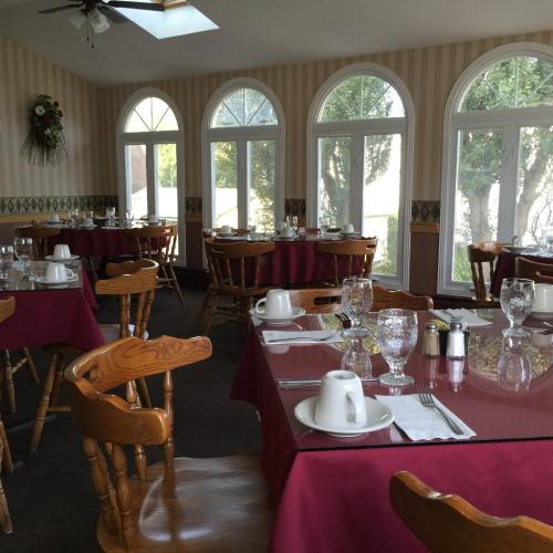 A dining room with wooden tables set for breakfast, featuring large arched windows and a cozy atmosphere.