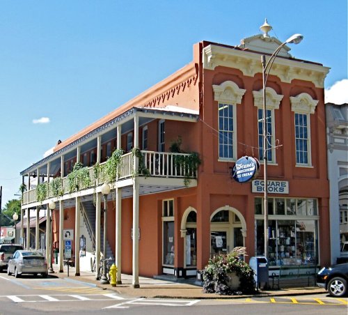 Historic building with a balcony, featuring a bookstore on the ground floor and greenery along the exterior.