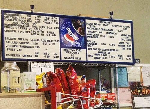 Menu board displaying food items and prices, including burgers, salads, breakfast options, and snacks.