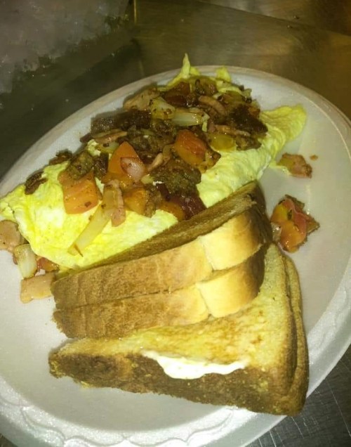 A plate with a hearty omelet topped with vegetables and meat, served alongside two slices of toasted bread.