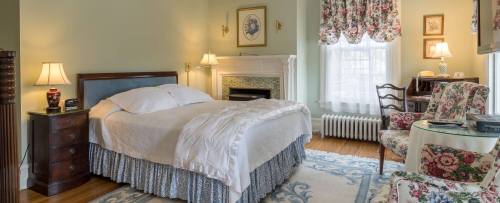 Cozy bedroom with a bed, floral decor, armchair, and soft lighting, featuring a vintage style and warm colors.