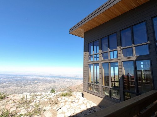 Modern building with large windows overlooking a vast landscape under a clear blue sky.