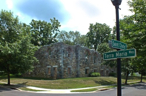 Ruins of a stone building surrounded by trees, with street signs for Saint Charles and Terra Maria Way nearby.