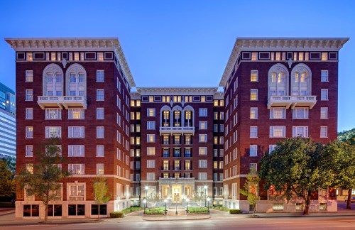 Historic brick building with ornate architecture, featuring large windows and a symmetrical facade, illuminated at dusk.