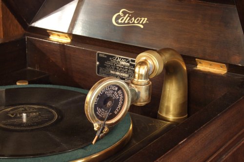 Close-up of an antique Edison phonograph with a brass horn and a vinyl record on the turntable.