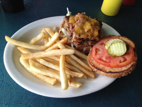 A plate with a burger topped with cheese and vegetables, served with a side of golden French fries.