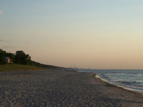 A serene beach at sunset, with gentle waves and a distant skyline on the horizon.