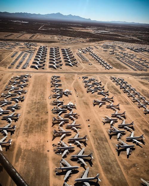 Aerial view of a large aircraft boneyard with numerous parked planes on a dry, sandy landscape.