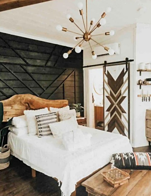 Cozy bedroom featuring a wooden bed, decorative pillows, a modern light fixture, and a stylish sliding door.