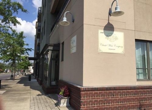 Exterior view of Classic Wine Company, featuring a sign and nearby planters, on a sunny day.