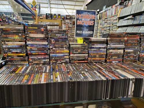 A display of stacked horror movie DVDs with a sign reading "Horror Movies - Price as Marked."