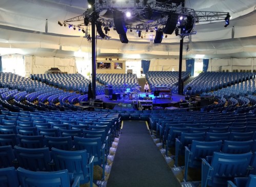 A spacious concert venue with blue seats, a stage set up with instruments, and soft lighting.