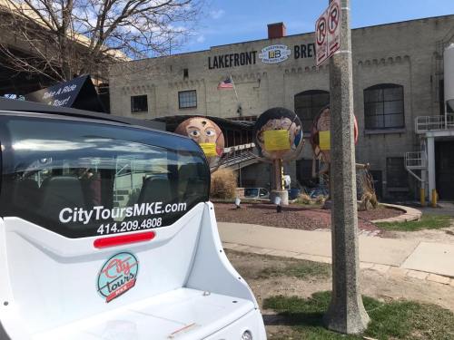 A view of a City Tours vehicle with large, colorful sculptures in the background near Lakefront Brewery.