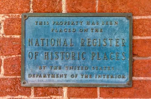 Plaque on a brick wall indicating the property is on the National Register of Historic Places by the U.S. Department of the Interior.