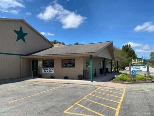 Exterior of Brady's Restaurant with a sign for curbside pickup and a star on the building, surrounded by parking spaces.
