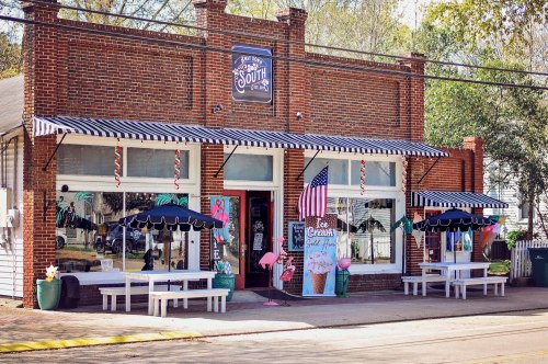 Charming ice cream shop with striped awnings, colorful decor, and an American flag outside on a sunny day.