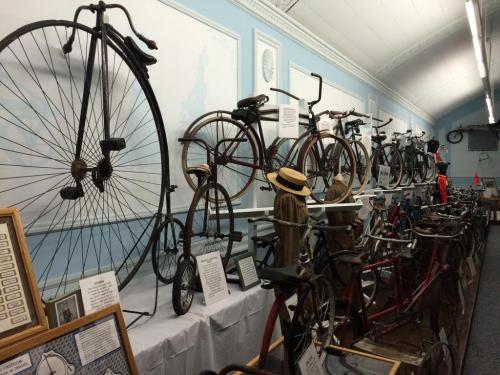 A display of vintage bicycles, including penny-farthings and early models, in a museum setting.