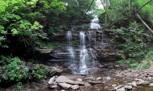 A serene waterfall cascading over rocky terrain, surrounded by lush green foliage and trees.