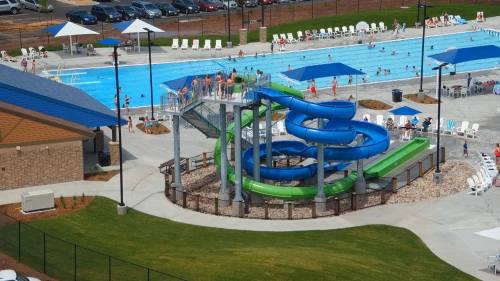 Aerial view of a water park featuring a large pool, water slides, and people enjoying the facilities.