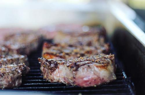 Grilled steaks sizzling on a barbecue, showcasing a perfectly seared crust and juicy interior.