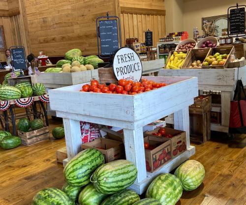 A vibrant market display featuring fresh produce, including tomatoes, melons, and various fruits in wooden crates.