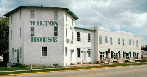 Historic Milton House building with green lettering, featuring a two-story structure and a modern addition.