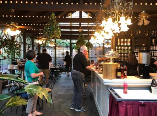 A cozy café interior with patrons at the counter, surrounded by plants and warm lighting.