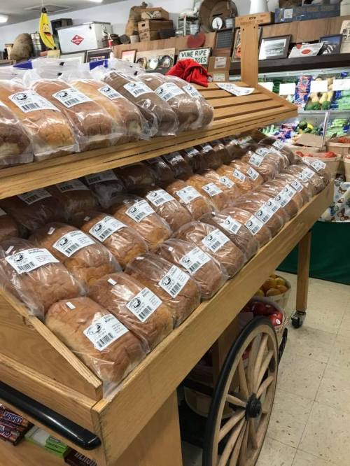 A wooden display rack filled with neatly packaged bread rolls in a grocery store.